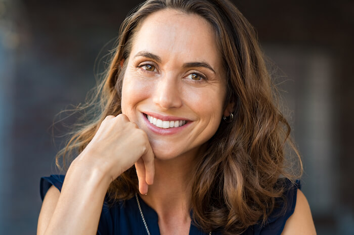 Pretty middle-aged woman smiling with hand on chin