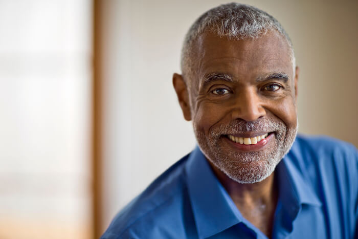 Mature man with gray hair and beard smiling at camera