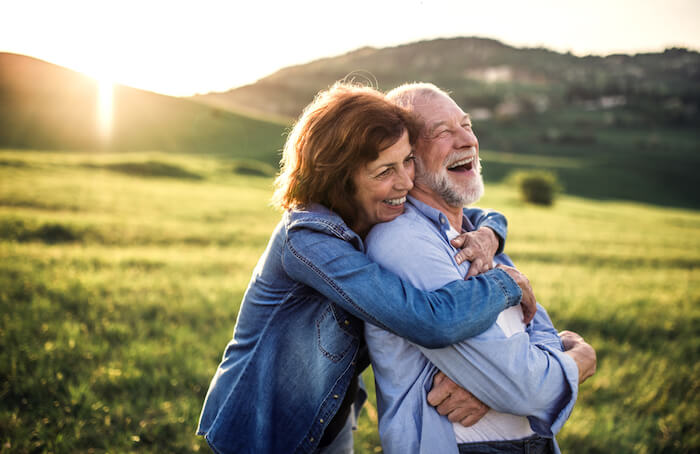 Mature couple laughing in green field
